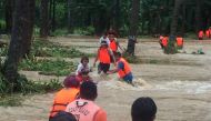 People cross floodwaters caused by tropical cyclone Kompasu during an evacuation assisted by the Philippine Coast Guard (PCG) at Brooke's Point, Palawan, in the Philippines, Ocotober 12, 2021, in this image obtained via social media. Philippine Coast Guar