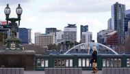 A lone woman, wearing a protective face mask, walks across an unusually quiet city centre bridge on the first day of a lockdown as the state of Victoria looks to curb the spread of a coronavirus disease (COVID-19) outbreak in Melbourne, Australia, July 16