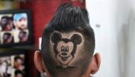 A customer poses for a photograph after he has his head shaved in the shape of Mickey Mouse by barber Rajwinder Singh Sidhu inside his shop in Dabwali town, in the northern state of Punjab, India, October 12, 2021. Picture taken October 12, 2021. REUTERS/