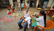 A healthcare worker gives a dose of the COVISHIELD vaccine against the coronavirus disease (Covid-19), manufactured by Serum Institute of India, to a man as others decorate the vaccination centre to celebrate the milestone of administering one billion COV