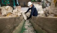 A worker loads shredded plastic to a machine to be molded into waterproof planks in the factory of social enterprise The Plastic Flamingo or The Plaf, in Muntinlupa, Philippines, October 18, 2021. The Plaf gathers plastics from restaurants, companies, and