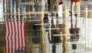 FILE PHOTO: A U.S. flag is reflected on the floor as passengers make their way through Reagan National Airport in Washington, U.S., July 1, 2016. REUTERS/Kevin Lamarque/File Photo/File Photo
