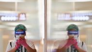 A person wearing a face shield and protective face masks uses her phone at the shopping mall on the first day of coronavirus restrictions lift on retail and dining in Bangkok and other high-risk areas to revive the economy, as the country battles its wors