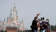 Visitors wearing protective face masks pose for a picture at Shanghai Disney Resort. Reuters/Aly Song/File Photo