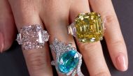 A staff wears an orange-pink diamond ring weighing 25.62 carats, a tourmaline and diamond ring weighing 9.88 carats and a yellow diamond ring weighing 25.88 carats, during a preview at Sotheby?s, before their auction sale in Geneva, Switzerland, November 2, 2021. REUTERS/Denis Balibouse
