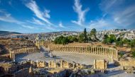 Oval Forum and long colonnaded street or cardo ancient Greco-Roman city Gerasa. Modern Jerash on background.