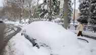 People walk past a car covered in snow following heavy snowfall in Shenyang, Liaoning province, China November 9, 2021. Picture taken November 9, 2021. China Daily via REUTERS