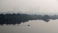 A man rows a boat as buildings shrouded in smog are seen in the background on the outskirts of Delhi, India, November 15, 2021. REUTERS/Adnan Abidi