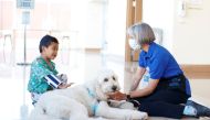 Kristin Gist and her dog Ollie greet patient Ricardo Martin, 6, with the return of the canine program at Rady Children's Hospital in San Diego, California, US, November, 11, 2021. Reuters/Mike Blake