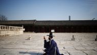 A man in Korean traditional costume Hanbok, wearing a protective face mask to avoid contracting the coronavirus disease (COVID-19), takes a photo of his girlfriend (not pictured) at Gyeongbok palace in Seoul, South Korea, November 17, 2021. REUTERS/Kim Hong-Ji