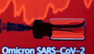 A vial and a syringe are seen in front of a displayed stock graph and words 