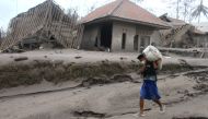 A villager carries his belongings during an evacuation following the eruption of Semeru mount volcano in Supiturang village, Lumajang, East Java province, Indonesia December 5, 2021, in this photo taken by Antara Foto/Ari Bowo Sucipto/via REUTERS
