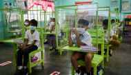 Students seated on chairs with plastic barriers attend a class as several schools in the Philippines' capital reopen for the first time since the coronavirus disease (COVID-19) pandemic, in Pasay City, Metro Manila, Philippines, December 6, 2021. REUTERS/Lisa Marie David