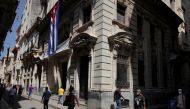 People walk under a Cuban flag at a commercial area amid concerns about the spread of the coronavirus disease (COVID-19), in Havana, Cuba, August 3, 2021. Picture taken August 3, 2021. REUTERS/Alexandre Meneghini

