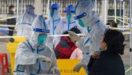 Medical workers in protective suits collect swabs from residents at a nucleic acid testing site during a third round of mass testing for the coronavirus disease (COVID-19) in Zhenhai district of Ningbo, Zhejiang province, China December 12, 2021. cnsphoto via REUTERS