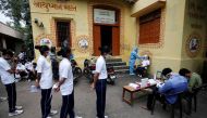 FILE PHOTO: A healthcare worker wearing personal protective equipment (PPE) takes a swab from a police officer for a rapid antigen test as others line up at a special testing center for Gujarat Police, amid the coronavirus disease (COVID-19) outbreak, in AHMEDABAD, India, August 17, 2020. REUTERS/Amit Dave/File Photo
