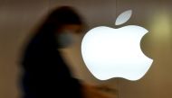 A woman walks past an Apple logo in front of an Apple store in Saint-Herblain near Nantes, France, September 16, 2021. REUTERS/Stephane Mahe/File Photo
