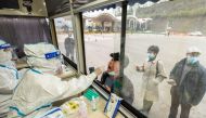 A medical worker in protective suit collects a swab from a man at a nucleic acid testing booth set up at a highway exit, following cases of the coronavirus disease (COVID-19) in the cities of Ningbo, Shaoxing and Hangzhou, in Ruian, Zhejiang province, China December 14, 2021. cnsphoto via REUTERS 