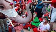 Students receive gifts from an elephant during a the visit of five elephants in Santa Claus costumes with giant face masks delivering hand sanitizers and promoting a 