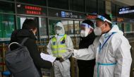Police and staff members wearing protective gear inspect the documents of a traveller at an entrance to a railway station, in Xian, Shaanxi province, China December 23, 2021. China Daily via Reuters 