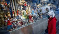 A woman wearing a face mask looks at a shop window with a nativity scene on display as coronavirus diseases (COVID-19) infections rise, in Rome, Italy, December 29, 2021. REUTERS/Guglielmo Mangiapane
