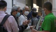 A staff member holds a QR code for the “LeaveHomeSafe” COVID-19 contact-tracing app to people lining up outside a community vaccination centre providing Sinovac Biotech's CoronaVac COVID-19 vaccine in Hong Kong, China December 2, 2021. REUTERS/Lam Yik

