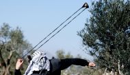 A Palestinian demonstrator uses a sling during a protest against Israeli settlements, West Bank, January 7, 2022. REUTERS.
