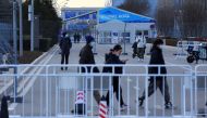 People walk behind a barrier outside a closed loop area designed to prevent the spread of the coronavirus disease (COVID-19) ahead of the Beijing 2022 Winter Olympics in Beijing, China, January 11, 2022. (REUTERS/Fabrizio Bensch)