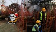 Workers plant bushes in the ground near the mascot of the Beijing 2022 Winter Olympics in Beijing, China, January 14, 2022. REUTERS/Thomas Peter