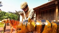 Nguyen Tan Phat stands in his yard with his Tiger carving works ahead of the Lunar New year in Hanoi, Vietnam January 18, 2022. Reuters/Stringer