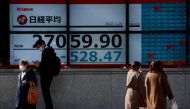 Passersby wearing protective face masks walk past a stock quotation board, amid the coronavirus disease (COVID-19) pandemic, in Tokyo, Japan January 25, 2022. REUTERS/Issei Kato