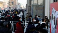People wearing face masks wait in line to enter a flagship merchandise store for the Beijing 2022 Winter Olympics on Wangfujing street in Beijing, China. Reuters/Carlos Garcia Rawlins