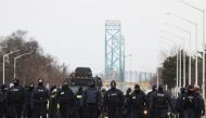 Police officers move along a road leading to the Ambassador Bridge, which connects Detroit and Windsor, after clearing demonstrators, during a protest against coronavirus disease (COVID-19) vaccine mandates, in Windsor, Ontario, Canada February 13, 2022. Reuters/Carlos Osorio