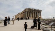 Tourists walk past the ancient Parthenon temple atop Acropolis hill in Athens, Greece, February 16, 2022. Reuters/Costas Baltas