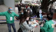 Staff members attend to residents lining up to receive the Sinovac Biotech vaccine against the coronavirus disease (COVID-19), at a community vaccination centre in Sha Tin district of Hong Kong, China February 18, 2022. REUTERS/Joyce Zhou


