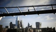 FILE PHOTO: The City of London financial district is seen as people walk over Millennium Bridge in London, Britain, February 16, 2022. REUTERS/Henry Nicholls