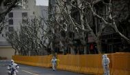 Staff in personal protective equipment (PPE) work by a barrier of an area under lockdown amid the coronavirus disease (COVID-19) pandemic, in Shanghai, China March 26, 2022. REUTERS/Aly Song
