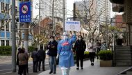 A worker in a protective suit shows a QR code to residents lining up for nucleic acid testing, as the second stage of a two-stage lockdown to curb the spread of the coronavirus disease (COVID-19) begins in Shanghai, China April 1, 2022. REUTERS/Aly Song
