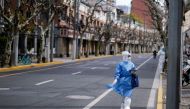 A worker in a protective suit keeps watch on a street, as the second stage of a two-stage lockdown to curb the spread of the coronavirus disease (COVID-19) begins in Shanghai, China April 1, 2022. REUTERS/Aly Song
 