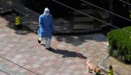 A person in personal protective equipment (PPE) walks a dog at a resident community, as the second stage of a two-stage lockdown has been launched to curb the spread of the coronavirus disease (COVID-19) in Shanghai, China April 3, 2022. REUTERS/Aly Song