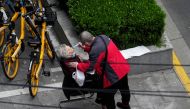 A man helps a woman to consume a packet of traditional Chinese medicine (TCM) Lianhua Qingwen, as she sits by the side of a road outside a residential compound, during a lockdown to curb the spread of the coronavirus disease (COVID-19) in Shanghai, China April 5, 2022. REUTERS/Aly Song