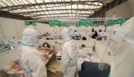 Medical workers in protective suits conduct ward rounds at Shanghai New International Exhibition Hall, which has been turned into a makeshift hospital for the coronavirus disease (COVID-19) patients, April 9, 2022. China Daily via Reuters 