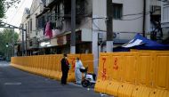 A worker in a protective suit keeps watch next to barricades set around a sealed-off area, during a lockdown to curb the spread of the coronavirus disease (COVID-19) in Shanghai, China April 11, 2022. Reuters/Aly Song