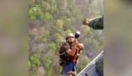 A rescuer carries a child to a helicopter during a rescue operation after mid-air collision of two cable cars on Sunday trapped nearly 50 people in a dozen cars, in Deoghar district, Jharkhand state, India in this still image taken from a handout video obtained April 12, 2022. Courtesy Indian Air Force/Handout via REUTERS