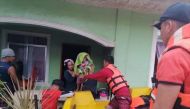 A rescuer assists a woman and a child onto a rescue boat, after the tropical storm Megi hit, in Capiz, Philippines April 12, 2022. Philippine Coast Guard/Handout via Reuters