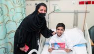 Ooredoo staff volunteers distributing gift vouchers to young patients at Hamad Hospital.