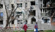 People walk near a residential building destroyed during Ukraine-Russia conflict in the southern port city of Mariupol, Ukraine April 22, 2022. REUTERS/Alexander Ermochenko/File Photo