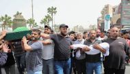 People carry the coffin of a woman as a father holds the body of his child who both died after a small dinghy carrying around 60 people sunk off the coast near the port city of Tripoli on Saturday night, during a funeral in Tripoli, Lebanon April 25, 2022. REUTERS/Mohamed Azakir