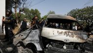 Police officers and members of the investigation team gather near a passenger van, after a blast at the entrance of the Confucius Institute University of Karachi, Pakistan April 26, 2022. REUTERS/Akhtar Soomro
