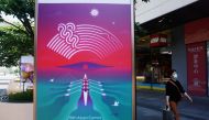 A person wearing a protective mask walks past a billboard for the 19th Asian Games Hangzhou 2022, amid the coronavirus disease (COVID-19) outbreak, in Hangzhou, Zhejiang province, China May 6, 2022. China Daily via REUTERS 